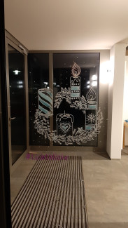 Adventskranz mit brennenden Kerzen ist auf eine Fensterscheibe gemalt