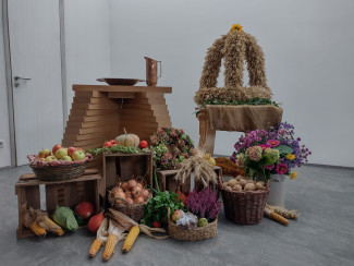 bebundene Getreidekrone, Obst und Gemüse liegen vor dem Taufbecken