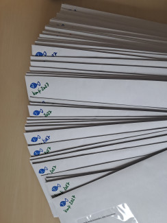 Ein Stapel Briefe, bei denen in der linken Ecke ein Fisch aufgestempelt ist und Konfi 2027 darunter steht