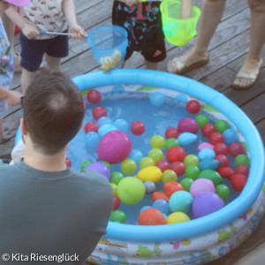 in einem Plantschbecken mit Wasser schwimmen bunte Luftballons