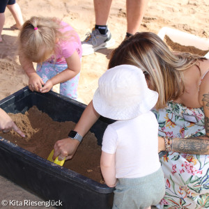Kinder graben in einer Kiste voller Sand nach einem Schatz